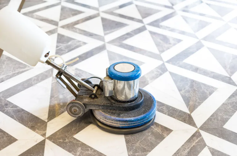 Floor buffer cleaning a geometric marble floor pattern with gray and white triangles.